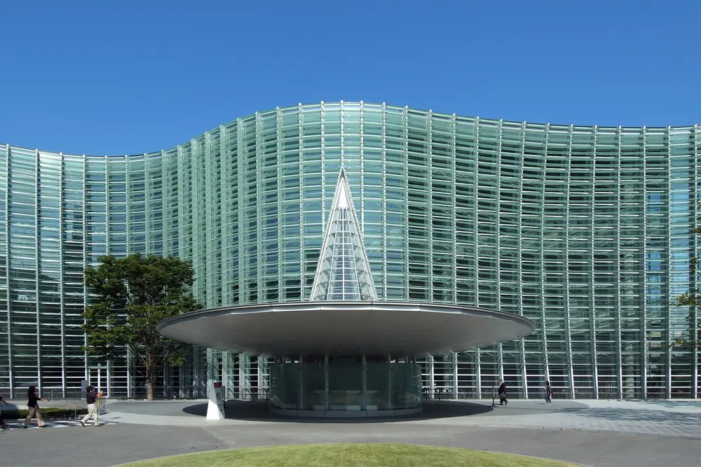 曲面ガラスの外壁と円錐形の入口を見せる国立新美術館